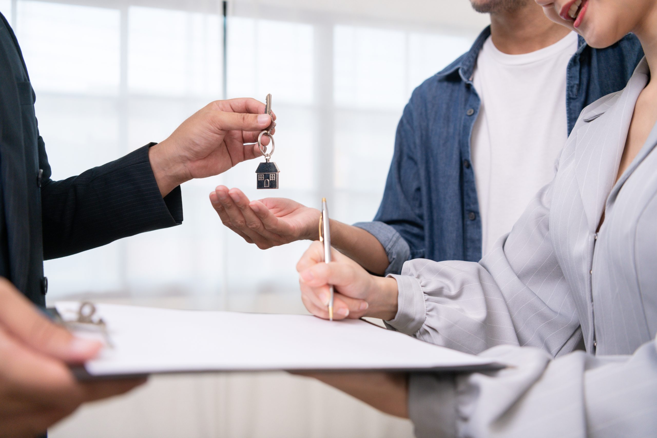 mortgage advisor handing over keys and person signing document